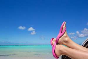 Female feet from the window of a car on a background of tropical beach
